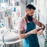 Men working at brewery and using a smartwatch application for fermentation process